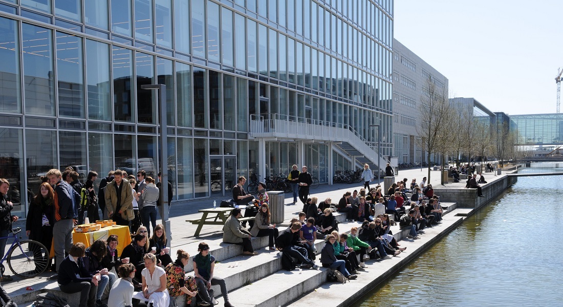 Students sitting by Emil Holm's canal in front of building 23.